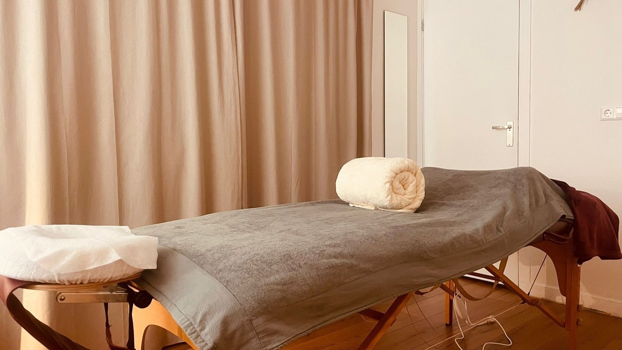 Massagetafel met een opgerolde handdoek en de hoofdsteun, voor linnen gordijnen